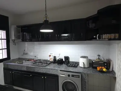 a kitchen with black cabinets and a washing machine at Havre de paix en plein coeur de Casa in Casablanca
