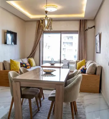 a dining room with a table and chairs and a couch at Charmante Deux Chambres et Salon Avec Jardin et Piscine à coté de plage in Casablanca