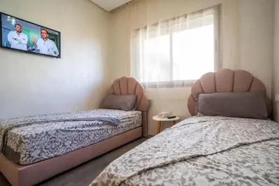 a bedroom with two beds and a tv on the wall at Charmante Deux Chambres et Salon Avec Jardin et Piscine à coté de plage in Casablanca