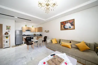 a living room with a couch and a kitchen at Studio Confortable avec Balcon, Piscine, Jardin et Aire de Jeux in Casablanca