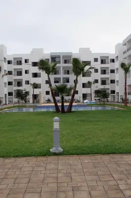 a building with palm trees in front of a park at APPARTEMENT luxe in Mansouria