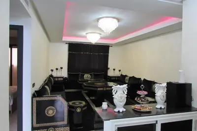 a living room with black chairs and a table with food at APPARTEMENT luxe in Mansouria