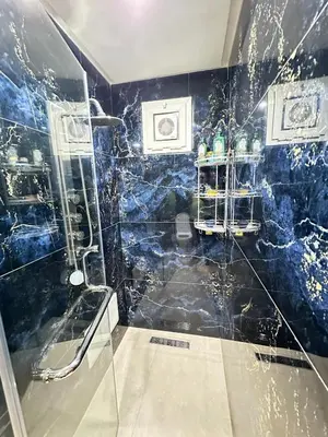 a bathroom with a shower with a blue tiled wall at Comfortable, quiet and beach apartment in Skhirat