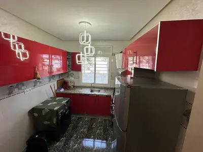 a kitchen with red cabinets and a refrigerator at Apartment 1 CH près de la plage in Oulad Akkou
