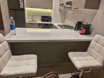 a kitchen with a counter with two chairs and a bottle of water at aeroperla 11 aeroprt casa blanca in Nouaseur