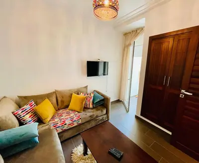 a living room with a couch and a tv at Janat KLK, tamaris beach in Tamaris