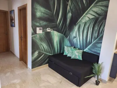 a couch in a room with a large leaf mural at Rita in Mohammedia