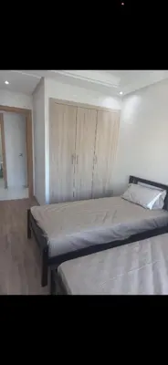 a bedroom with two beds and a cabinet at Residence Garden Paradise plage luxe in Bouznika
