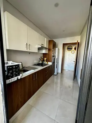 a large kitchen with wooden cabinets and a white refrigerator at APT Luxueux à Costa Beach 3 avec Piscine et accès Plage in Bouznika