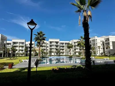 a large apartment building with a swimming pool and a street light at APT Luxueux à Costa Beach 3 avec Piscine et accès Plage in Bouznika