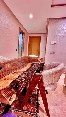 a living room with a wooden table and a chair at CAN STADIUM VIEW Luxurious Place Prestigia Hay Riad in Rabat
