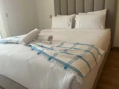 a large white bed with white pillows and a blanket at Appart idéal Face Gare Agdal in Rabat