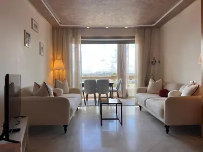 a living room with two couches and a table at Grand appartement la corniche vue panoramique sur Casablanca in Casablanca