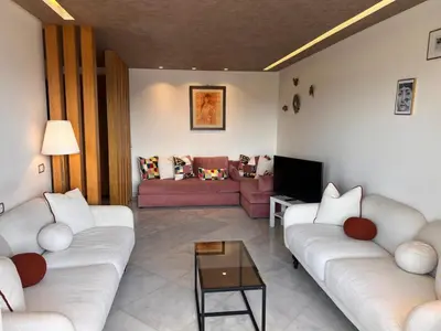 a living room with two couches and a tv at Grand appartement la corniche vue panoramique sur Casablanca in Casablanca
