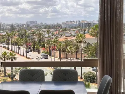 a room with a view of a city with palm trees at Grand appartement la corniche vue panoramique sur Casablanca in Casablanca