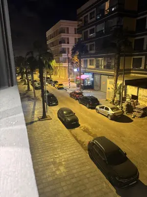 a city street at night with cars parked on the street at Studio au parc calme in Mohammedia