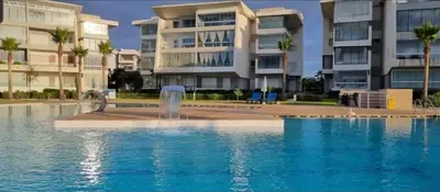 a swimming pool with a fountain in front of a building at Sidi Rahal Blue View 3, front mer, accès plage 1 Piscine in Sidi Rahal