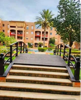 a wooden bridge with stairs in front of a building at Joli appartement Ricoflores El Mansouria in O Ben Slimane