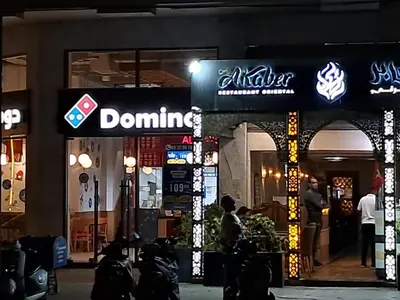 a domino shop with people standing outside of it at night at Riviera Escape - Appart Neuf Climatisé avec Balcon à Maarif Anfa in Casablanca