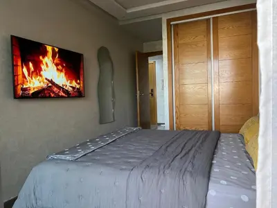 a bedroom with a bed with a fire painting on the wall at Riviera Escape - Appart Neuf Climatisé avec Balcon à Maarif Anfa in Casablanca