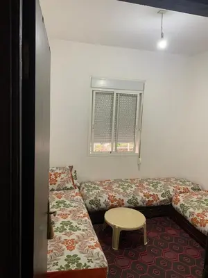 a room with two beds and a table and a window at Tms in Sidi Yahia az Zaʼer
