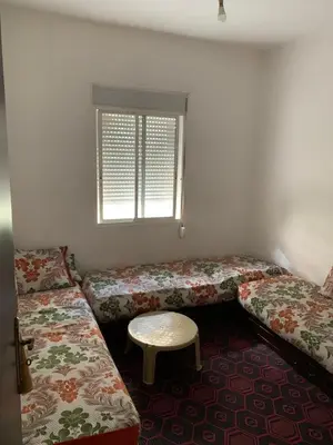 a room with two beds and a table and a window at Tms in Sidi Yahia az Zaʼer