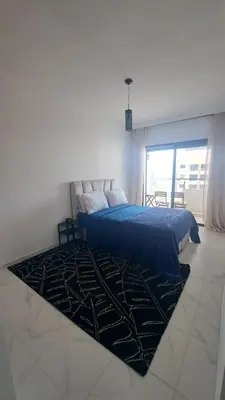 a bedroom with a blue bed and a rug at Bel appartement près de la plage pour Famille in El Harhoura