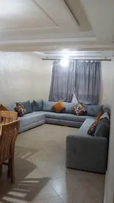 a living room with a blue couch in front of a window at Le calme de Bouznika in Bouznika
