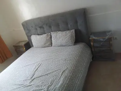 a large bed with a gray headboard in a bedroom at Le calme de Bouznika in Bouznika
