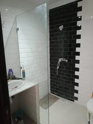 a bathroom with a glass shower and a sink at Le calme de Bouznika in Bouznika