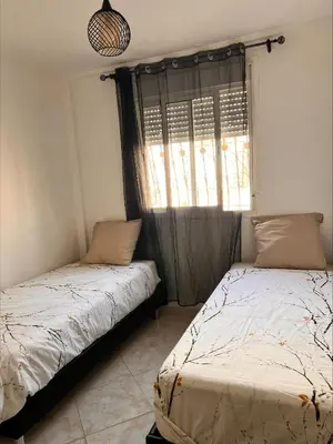two beds in a room with a window at BOUZNIKA PLAGe in Bouznika