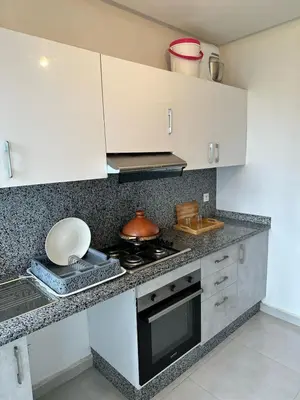a kitchen with white cabinets and a stove top oven at Appartement à Témara - Élégance et confort in Temara