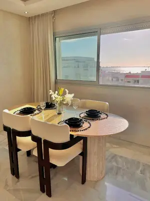a dining room with a table and chairs and a window at Luxury Beachview Apartment La siesta beach resort in Mohammedia