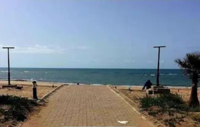 a brick path on a beach with the ocean at appartement ola blanca 2 in Dar Hamida