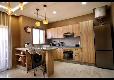 a kitchen with wooden cabinets and a stainless steel refrigerator at Havre de paix au bord de mer in Pont Blondin