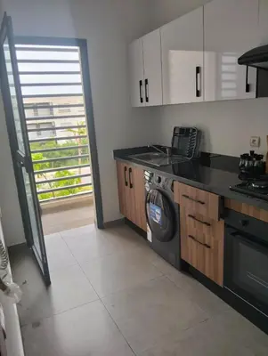 a kitchen with a stove and a washing machine at Appartement avec piscine El mansoria Mohammedia in Mansouria