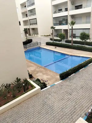 a swimming pool in front of a building at Appartement avec piscine El mansoria Mohammedia in Mansouria