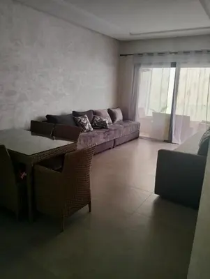 a living room with a couch and a table at Appartement avec piscine El mansoria Mohammedia in Mansouria