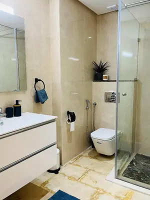 a bathroom with a toilet and a glass shower at Elegant & Cozy Beach Apartment in Mohammedia