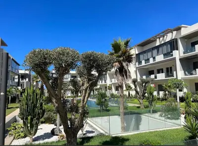 an apartment complex with a swimming pool and palm trees at Évasion de luxe Tamaris in Tamaris