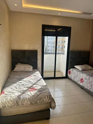 a bedroom with two beds and a large window at appartement a 1 min de la plage in Casablanca