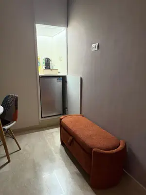 a living room with a ottoman in front of a kitchen at Studio Perla Sofé in Nouaseur