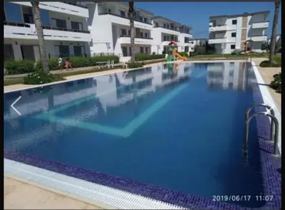 a large blue swimming pool in front of some buildings at Marbella Beach apartement holiday 2 chambres,piscine et plage in Mansouria