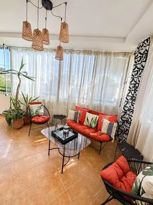 a living room with a red couch and a table at Escapade Tropicale at Jardins Cherrat in Bouznika Bay in Bouznika