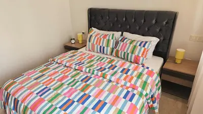a bed with a colorful comforter and a pillow at Bright 2BR Apartment in Maârif, Ideal for Families & Business Travelers in Casablanca