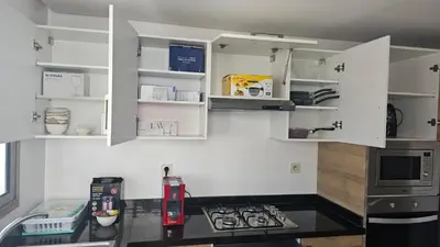 a kitchen with white cabinets and a black counter top at Bright 2BR Apartment in Maârif, Ideal for Families & Business Travelers in Casablanca