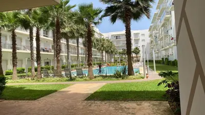 an apartment complex with a swimming pool and palm trees at Appartement de haut standing,4 piscines in Bouznika