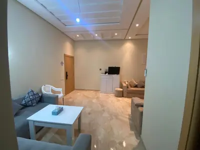 a living room with a couch and a table at Appartement de haut standing,4 piscines in Bouznika