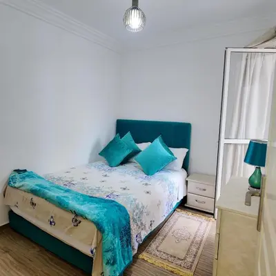 a bedroom with a bed with blue pillows at Appartement Sidi Rahal Casablanca - proche du SHEMPARK payant, Sidi rahal et tamaris plage in Sidi Rahal