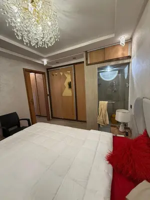 a bedroom with a large white bed and a chandelier at Comfortable apartment temara in Temara